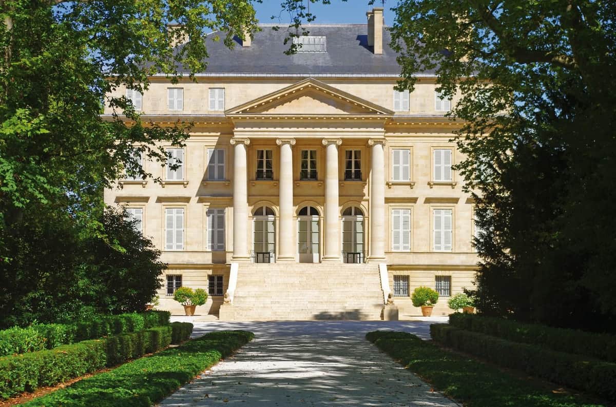 Médoc: Half-Day Wine Tour from Bordeaux A grand neoclassical building with six columns, arched windows and wide stone steps. Set against a backdrop of manicured hedges and trees.