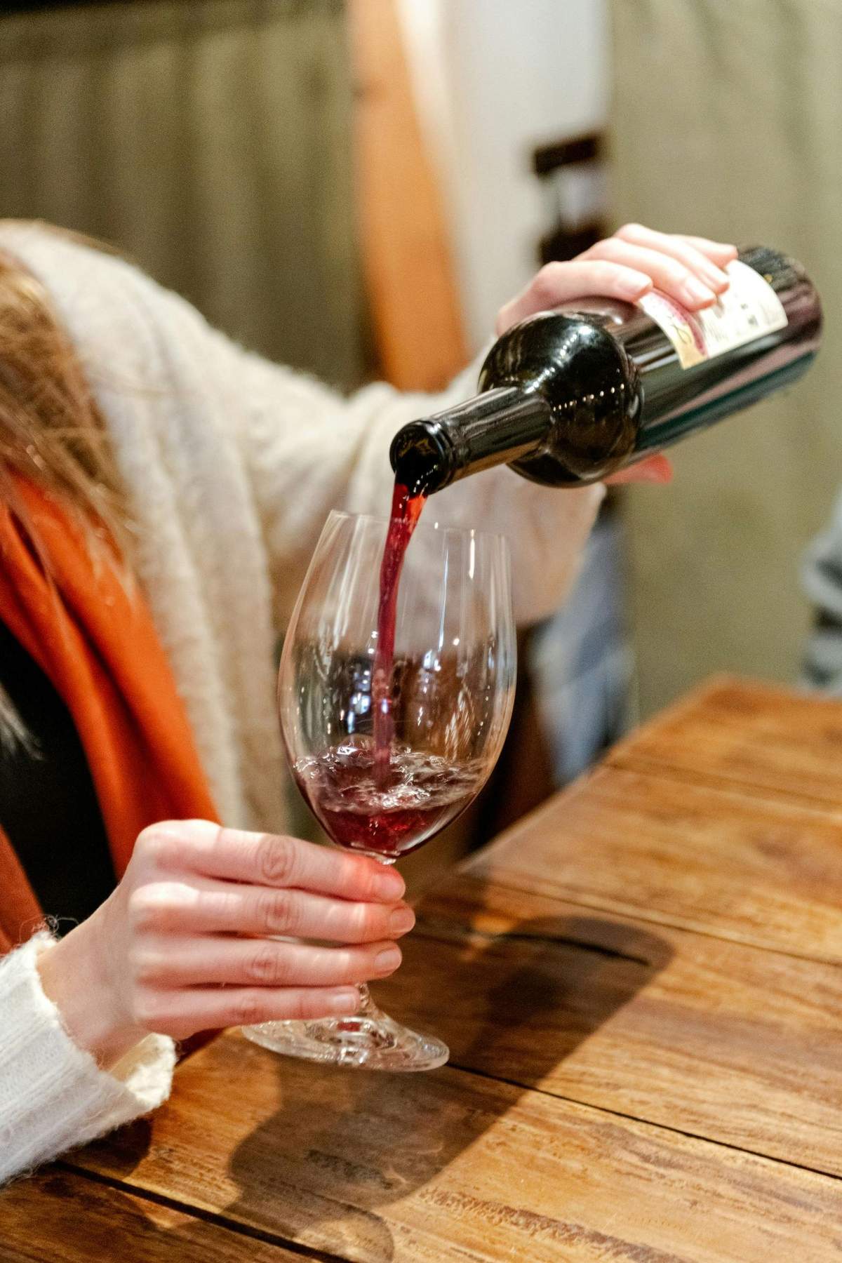 Seattle: Wine, Bread, Cheese & Chocolate Tour A person pouring red wine into a glass on a wooden table, with a blurred background.