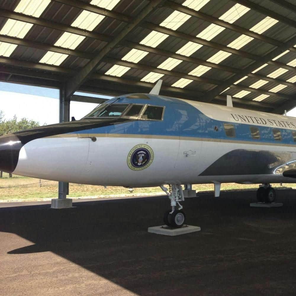 Texas Hill Country and LBJ Ranch Experience from Austin A blue and white airplane with "United States" and a presidential seal, parked under a roofed structure.