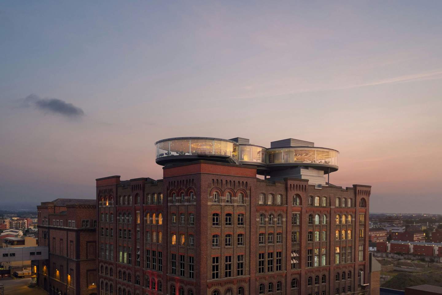 Guinness Storehouse A red brick industrial-style building with modern glass circular extensions on the rooftop, set against a dusk sky.