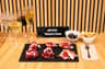 A table setup for a ham tasting masterclass, featuring ham slices on a slate, wine glasses, and small bowls of sides.